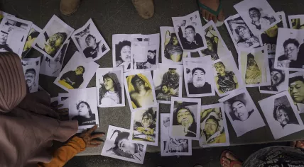 People looking for their relatives inspect photographs of soccer riot victims provided by volunteers to help them identify their family members in Malang, East Java, Indonesia, Sunday, Oct. 2, 2022. Panic at an Indonesian soccer match Saturday left a number of people dead, most of whom were trampled to death after police fired tear gas to dispel the riots. 