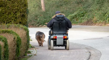 A man drives an electric wheelchair down the road.