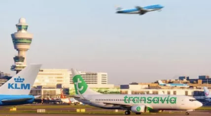 A KLM aircraft takes off above a Transavia airplane on the ground