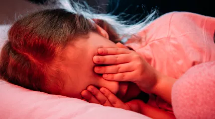 Scared child covering her eyes