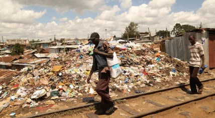 People walking past mounds of trash in Nairobi, Kenya