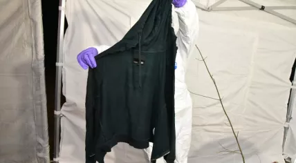 Investigator holding up a piece of clothing of a woman found dead on Wiesselseweg in Wenum-Wiesel on 23 March 2023