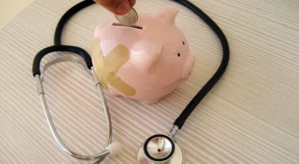 A metaphor for health insurance costs, visualised by piggy bank at the doctor.
