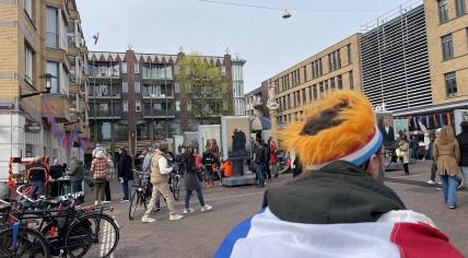 A man wearing a Dutch flag walking through the Bredeweg Festival in Amsterdam on King’s Day. 27 April 2023