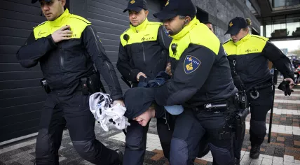 Police officers carry away a protester arrested for running at French President Emmanuel Macron while he visited the Amsterdam Science Park with King Willem-Alexander, 12 April 2023