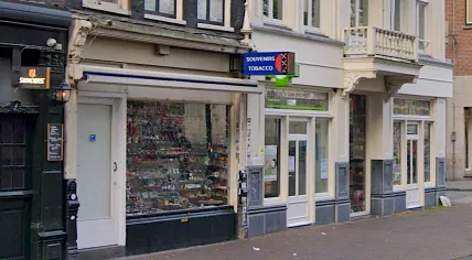 The souvenir shop at Damstraat 2A, a pharmacy, and another souvenir shop at the intersection with Nes in September 2021