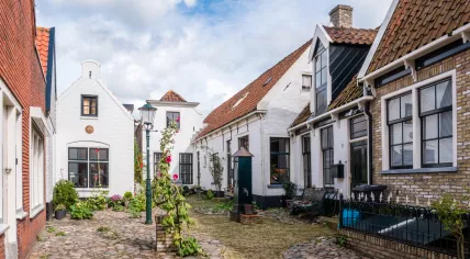 Historic courtyard Hofje with old white houses and water pump in Weverstraat of Den Burg town on Texel island 