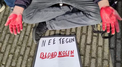 A protestor with a sign saying "No to blood coal" during a demonstration in Amsterdam. 21 April 2023