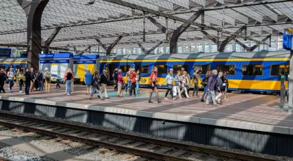 A crowded platform at Rotterdam Central Station with an NS train in the background