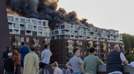 Bystanders watch a raging fire in an apartment building on Joan Muyskenweg in Amsterdam-Oost.