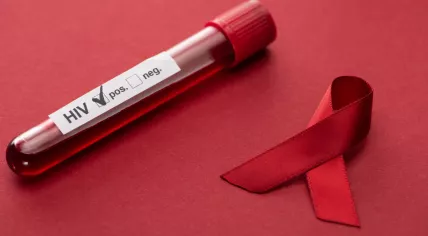 The red AIDS awareness ribbon with a positive HIV blood test on a red background