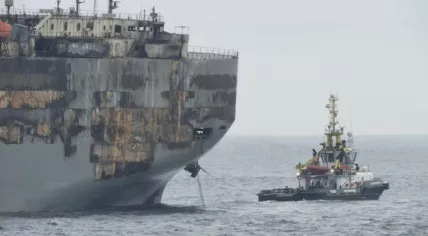 The burnt-out and damaged Fremantle Highway connected to a tug boat, 2 August 2023