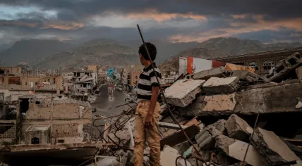  A Yemeni child stands in rubble that used to be homes in the city of Taiz, 22 August 2016