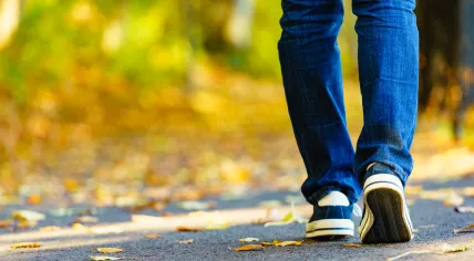 Person wearing sneaker and jeans trousers walking outdoor.
