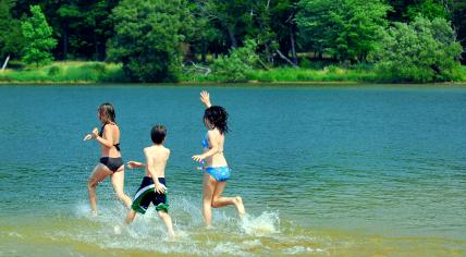 Three children running into a lake