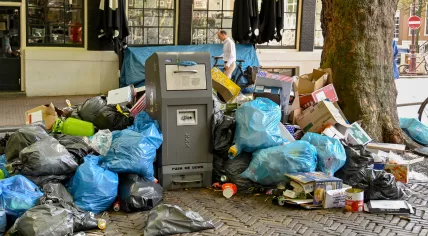Piles of rubbish bags dumped alongside a waste bin on a street in the center of Amsterdam, August 2022