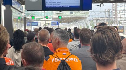 Formula 1 fans wait at Amsterdam Centraal for the train to get to the Dutch Grand Prix in Zandvoort.