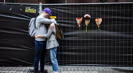 Two people embrace in front of a home on Heiman Dullaertplein in Rotterdam, where a woman, 39, and her daughter, 14, were shot dead a day earlier. 29 September 2023