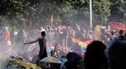 Extinction Rebellion protesters standing in the spray of a police water canon during a highway blockade on the A12 highway in The Hague, 9 September 2023
