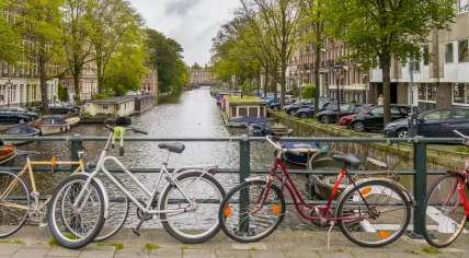 Cars, bicycles, and boats parked along an Amsterdam canal