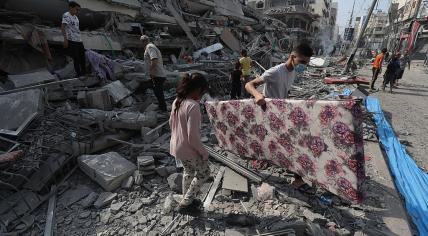 Palestinians inspect the ruins of Aklouk Tower destroyed in Israeli airstrikes in Gaza City on 8 October 2023