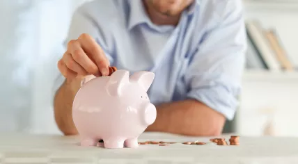 Man putting a coin into a piggy bank