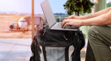 An airplane passenger working on a laptop at an airport