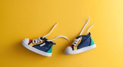 Colorful baby shoes on a yellow background