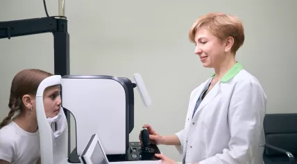 An ophthalmologist examines the eyes of a girl on modern equipment
