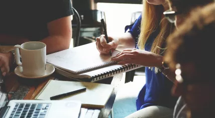 A group of people working around notebooks, laptops and coffee