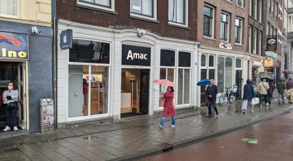 People walking past the Amac retail store on Prins Hendrikkade in Amsterdam. 22 April 2023