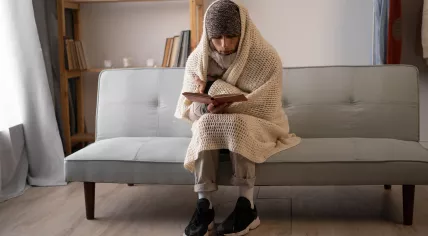 Man wearing warm clothes indoors due to lack of heating. 