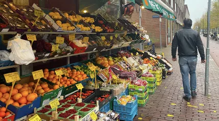 A customer walks past an Amsterdam bodega's produce set up in front of the grocery store. 22 November 2023