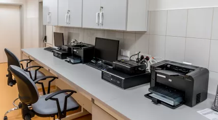 Electronics, computers, and printers on a long desk in an office