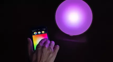Female hand using Apple iPhone to control a Philips Hue smart home light