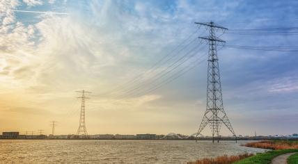 Electricity poles and power lines in the lake Buiten IJ with the Amsterdam district IJburg in the background