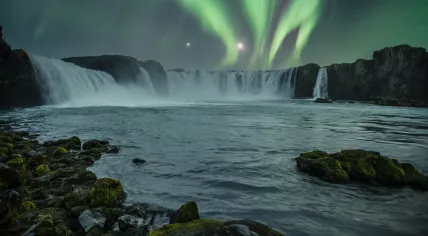 The Northern Lights in the sky above the Godafoss waterfall in Iceland. November 2021