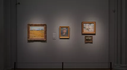 The Vincent van Gogh paintings Wheat Field (1888), Riverbank with Trees (1887), and View of Amsterdam from Central Station (1885) hanging with a self-portrait of the Dutch artist in the Rijksmuseum, March 2024