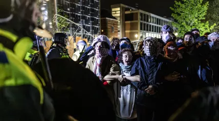 Pro-Palestinian demonstrators cling to each other as the riot police remove them from the University of Amsterdam campus, 7 May 2024