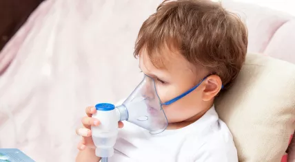 Sick boy sitting with a nebulizer at home