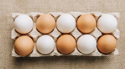 White and brown eggs laying in egg carton on sackcloth