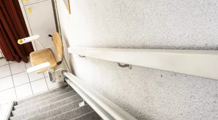 Automatic stair lift on staircase taking elderly people and disabled persons up and down in a house