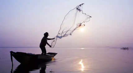 A fisherman catching fish with a cast net. 