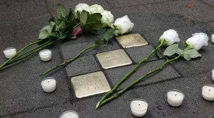 Flowers laid at stumbling stones memorializing Jewish people who were deported and killed during World War II