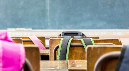 Backpacks hanging on the backs of chairs in a primary school classroom