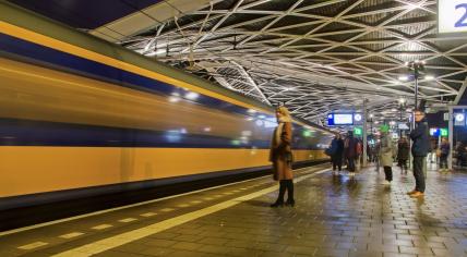 People waiting on the platform of Tilburg station while a NS intercity enters the station