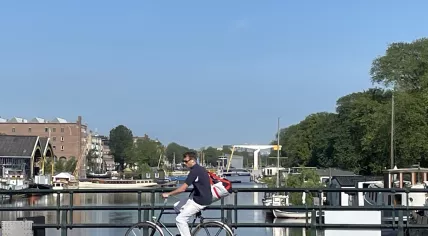 Looking west as a bicyclist crosses Oostenburgergracht in Amsterdam on a sunny morning. 15 July 2024