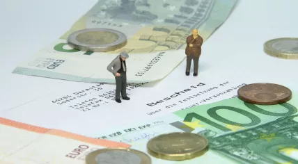 Depiction of two entrepreneurs staring at a tax assessment with euro banknotes and coins
