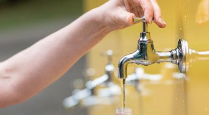 Woman filling a plastic bottle with water from a tap