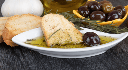 Bread dipped in olive oil with herbs and olives